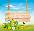 Easter Holiday Background with colofrul eggs in green grass and wooden sign.