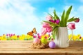 Easter holiday concept with beautiful tulip flowers bouquet and Easter eggs on wooden table over beautiul sky background Royalty Free Stock Photo