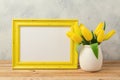 Easter holiday concept with blank photo frame and tulip flowers on wooden table Royalty Free Stock Photo