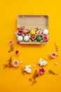 Easter holiday concept with cute handmade colorful eggs, egg tray, bunny and flowers on yellow background. Flat lay concept, top Royalty Free Stock Photo