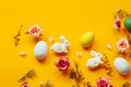 Easter holiday concept with cute handmade colorful eggs, egg tray, bunny and flowers on yellow background. Flat lay concept, top Royalty Free Stock Photo