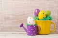 Easter holiday concept with egg decoration in yellow cup and watering can