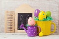 Easter holiday concept with painted eggs decoration, cup and watering can