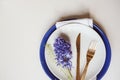 Easter holiday festive dining table with plate, golden cutlery and hyacinth flower on white background