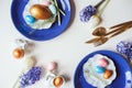 Easter holiday greeting card, dining table with plate, golden cutlery, painted eggs and hyacinth flower on white background Royalty Free Stock Photo