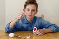 Easter Holiday at Home. Young blonde boy coloring drawing Easter Eggs