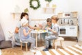 Easter holiday: mother and children sit at the table and paint eggs with paints.