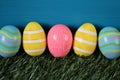 Easter holiday.Multicolored striped easter eggs on green grass on turquoise background..Spring festive easter background Royalty Free Stock Photo