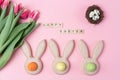 Easter holiday background with colored eggs in bunny ears shaped egg cups, pink flowers tulip , Happy Easter wooden