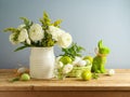 Easter holiday still life with white flowers bouquet and Easter eggs decoration on wooden table over gray background Royalty Free Stock Photo