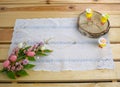 Easter holiday. White lace napkin, chickens toys on slice and bouquet of flowers with eggs on wooden background. Vintage backgroun Royalty Free Stock Photo