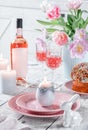 Easter holidays table, pink wine in glasses, Easter cake, color eggs, served plates, flowers tulips, candles on white background Royalty Free Stock Photo