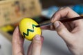 Easter, holidays, tradition and people concept - close up of woman hands coloring easter eggs with colors and brush. Happy Easter