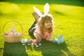 Easter kids boy in bunny ears paint easter eggs outdoor. Cute child in rabbit costume with bunny ears having fun and Royalty Free Stock Photo