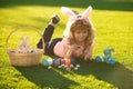 Easter kids boy in bunny ears painting easter eggs outdoor. Cute child in rabbit costume with bunny ears having fun in Royalty Free Stock Photo