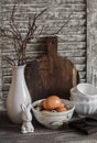 Easter kitchen still life - eggs in a bowl, a vase with dry twigs, ceramic rabbit, vintage crockery and cutting board