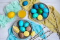 Easter layout. Yellow, blue and green eggs on plates, brown and yellow macaroons, lemons on a light background. View