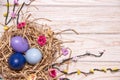 Easter light wooden background with colored eggs in a nest