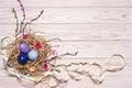 Easter light wooden background with colored eggs in a nest