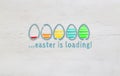 Easter is loading concept with colorful eggs on light wood Royalty Free Stock Photo