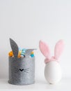 Easter minimalistic decor in the interior. A gray felt basket in the shape of a hare and a large ceramic egg with ears