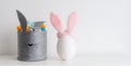 Easter minimalistic decor in the interior. A gray felt basket in the shape of a hare and a large ceramic egg with ears