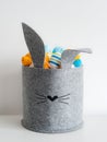 Easter minimalistic decor in the interior. A gray felt basket in the shape of a hare and a large ceramic egg with ears