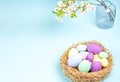Easter multi-colored eggs with branches of blossoming cherry in a vase on a blue background Royalty Free Stock Photo