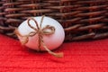 Easter one white egg with ribbon on red background with basket with copy space. Royalty Free Stock Photo