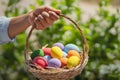 Easter Painted Eggs In Basket Hand Holding On Green Background