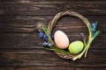 Easter painted eggs in a wicker wreath on a dark wooden background with blue scilla flowers and copy space Royalty Free Stock Photo