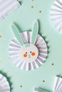 Easter paper craft for kids. paper DIY bunny on mint background. spring decor.