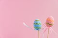 Easter pink and blue decorated eggs stand on a wooden sticks on pink background. Minimal easter concept. Happy Easter card with Royalty Free Stock Photo