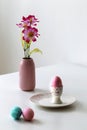 Easter pink egg in small bowl with pink vase with tulip