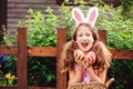 Easter portrait of happy child girl in funny bunny ears playing egg hunt outdoor Royalty Free Stock Photo