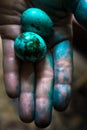 Easter quail eggs painted blue on a paint stained woman& x27;s palm. Closeup view, selective focus