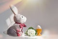 Easter rabbit toy and a cheerful egg in a nest on a white gray background Royalty Free Stock Photo