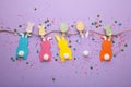 Easter rabbits handmade from colored paper on a rope with clothespins easy crafts for children on a purple background