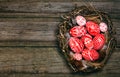 Easter red eggs with folk white pattern inside bird nest on right side of rustic wood board. Top view. Ukrainian traditional eggs