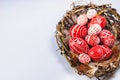 Easter red eggs with folk white pattern inside bird nest on white background. Top view. Ukrainian traditional eggs