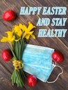 Easter red eggs, medical masks from coronavirus, a cup of tea on a vintage table, yellow daffodils, white crocheted napkin.