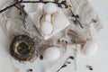 Easter rustic flat lay. Natural eggs, feathers, willow branches, nest on aged white table. Stylish rural Easter still life in
