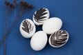 Easter rustic or scandinavian composition with white egg decorated black feather on classic blue background. Farming and healthy Royalty Free Stock Photo