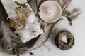 Easter rustic still life, selective focus. Easter natural eggs in tray, feathers, willow branches, nest on burlap on white wooden