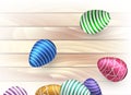 Easter, scattering green, blue, violet, pink, gold eggs with an ornament on a light festive on wooden boards background.
