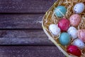 Multicolored easter eggs in a basket on a brown wooden table, Ea