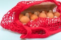 Easter shopping concept. Buying eggs. Close-up of natural raw eggs in a cardboard egg box and in a red string bag Royalty Free Stock Photo