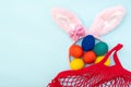 Easter shopping concept. Hand painted Easter eggs, pink bunny ears and a red shopping bag on a blue background Royalty Free Stock Photo
