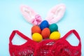 Easter shopping concept. Hand painted Easter eggs, pink bunny ears and a red shopping bag on a blue background Royalty Free Stock Photo