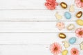 Easter side border with eggs, paper flowers and wooden bunnies against a white wood background